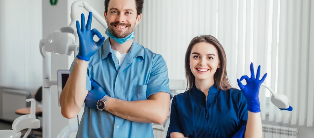 photo-smiling-dentist-standing-with-arms-crossed-with-her-colleague-showing-okay-sign